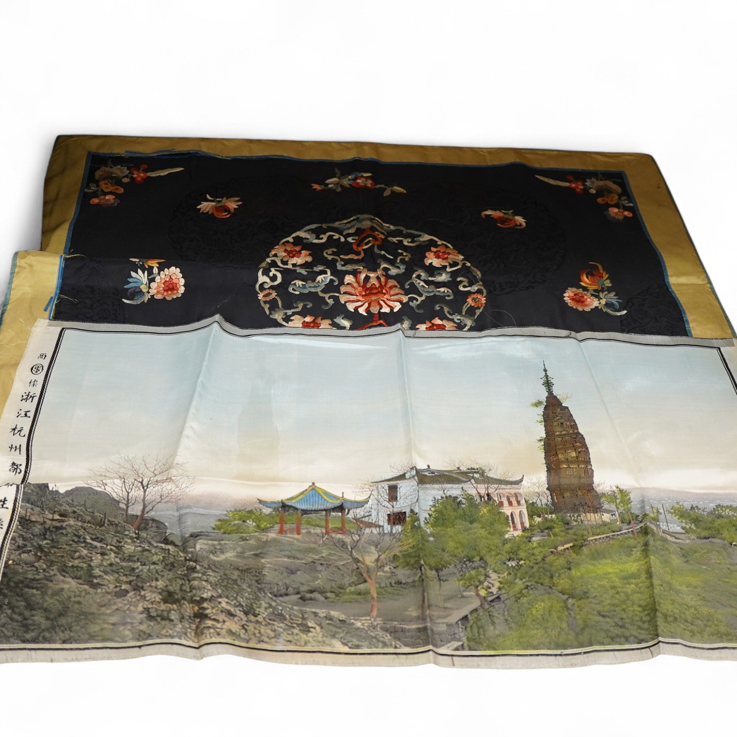 An early 20th century Chinese blue silk and coloured floral embroidered table cover, with a later Chinese printed panel of a house, pagoda and monument along a river bank, embroidery 78cm x 62cm. Condition - the edging t